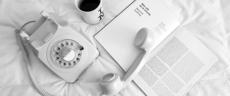 contact us illustration image A vintage telephone beside a coffee cup and an open magazine on a bed.