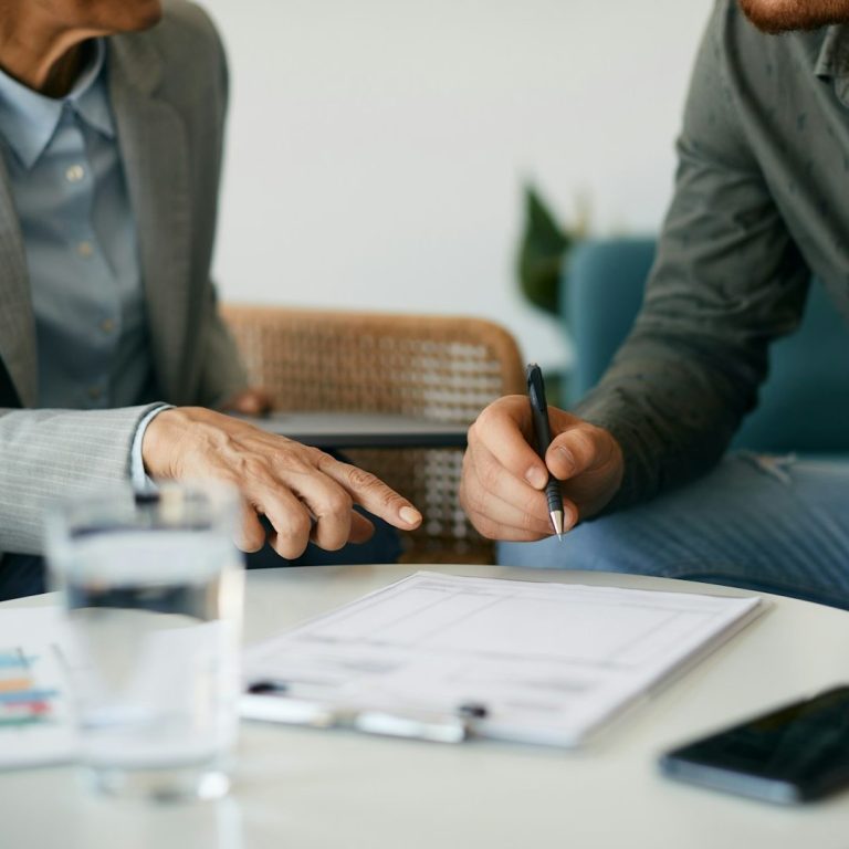 Two people discussing documents with a glass of water and a phone on the table.
